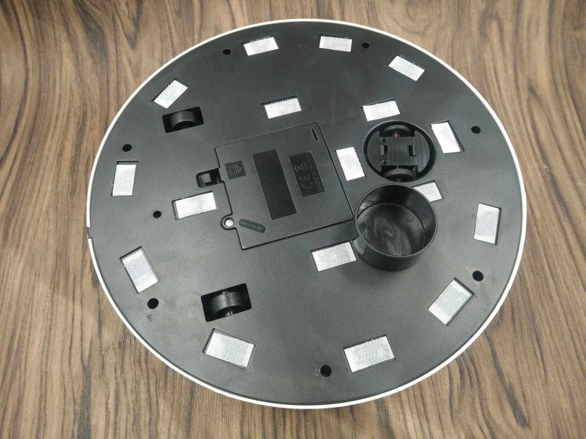 Black or white compact robot vacuum cleaner on a hardwood floor.