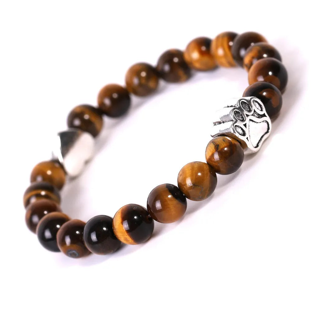 Close-up of a tiger's eye and Indian agate bead bracelet with a central geometric dog's paw charm on a wrist.