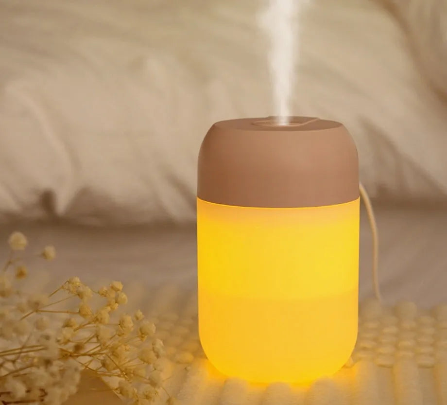White cylindrical mini USB humidifier on wooden surface with charging cable
