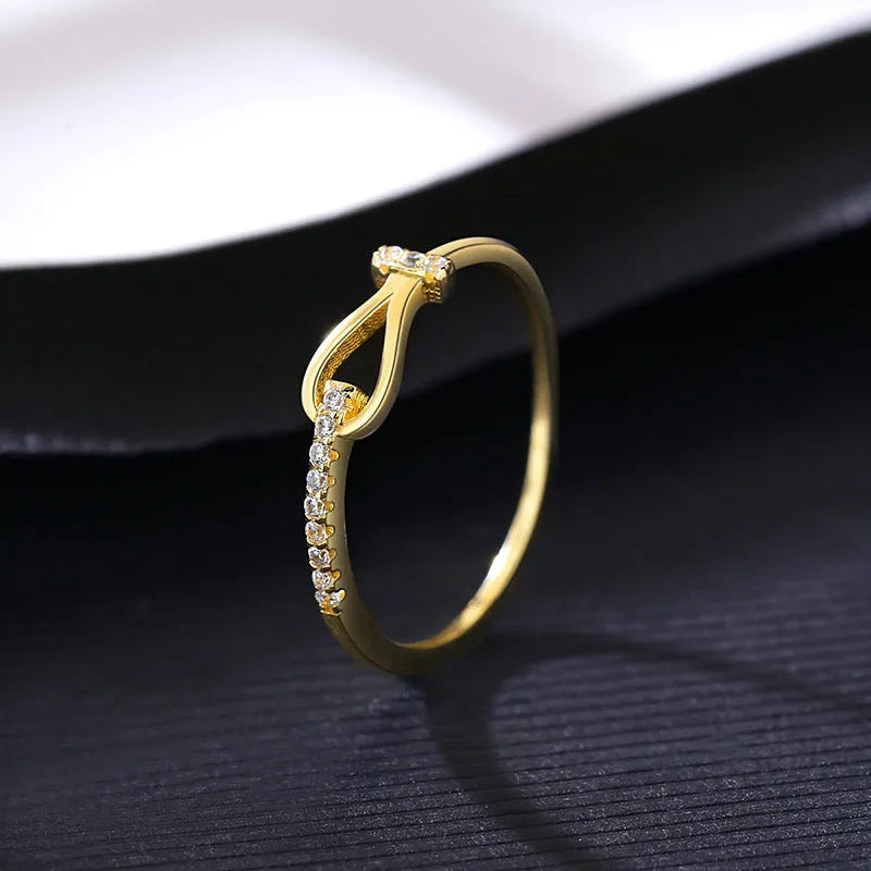 Gold electroplated silver bow ring with inlaid zirconium for women on plain background