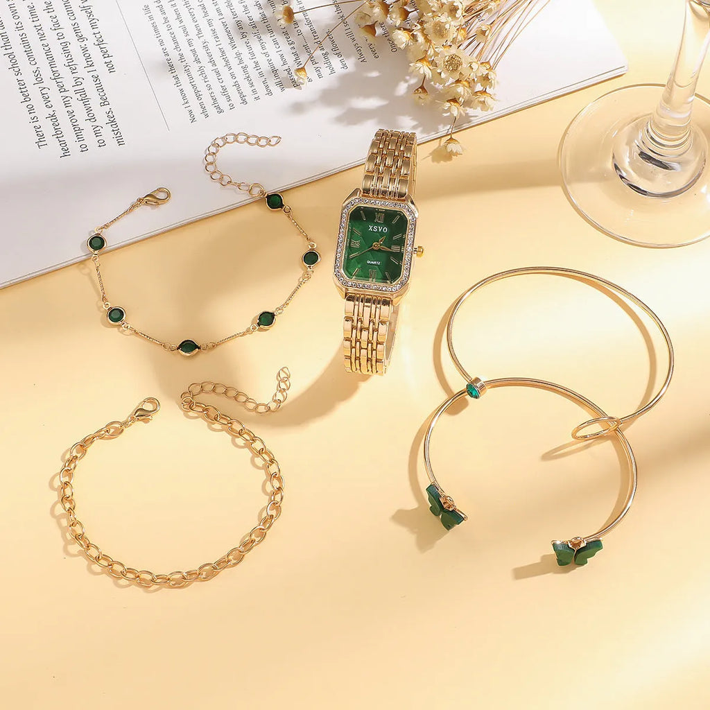 Gold green square steel ladies watch and four matching butterfly jewellery bracelets laid out as a set.