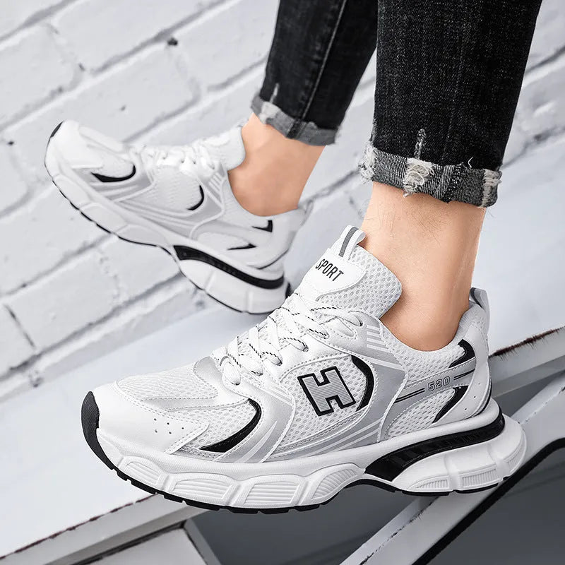 Men's solid colour mesh running shoes with a plastic sole, shown in black, white and grey, and white and orange.