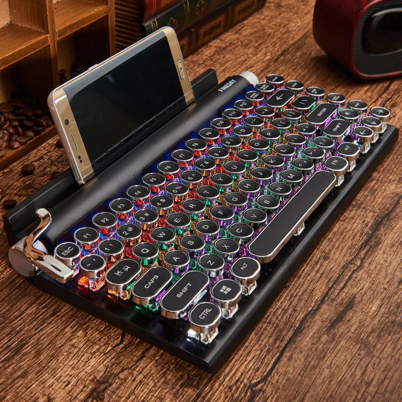 Black retro-style mechanical keyboard with typewriter keycaps and multi-colour backlighting on a desk.