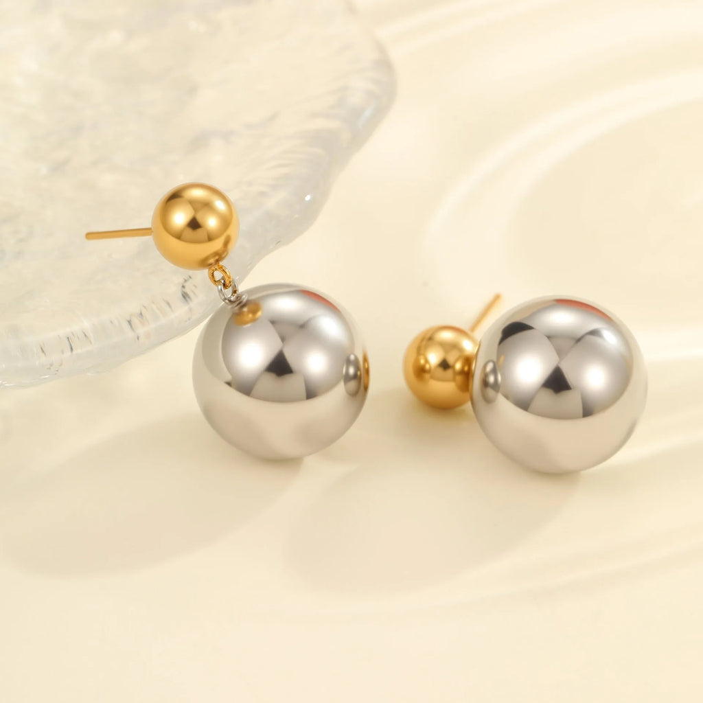 Pair of round bead stud earrings with gold plating and colour-block design on a woman's earlobe.