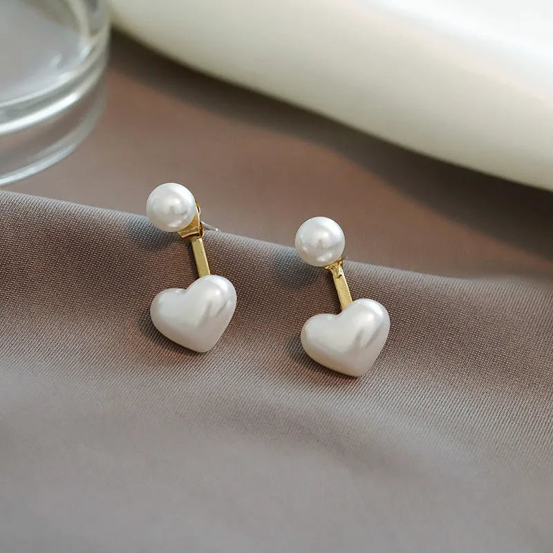 Close-up of women's simple heart-shaped stud earrings with a pearl-like finish and Korean style design.