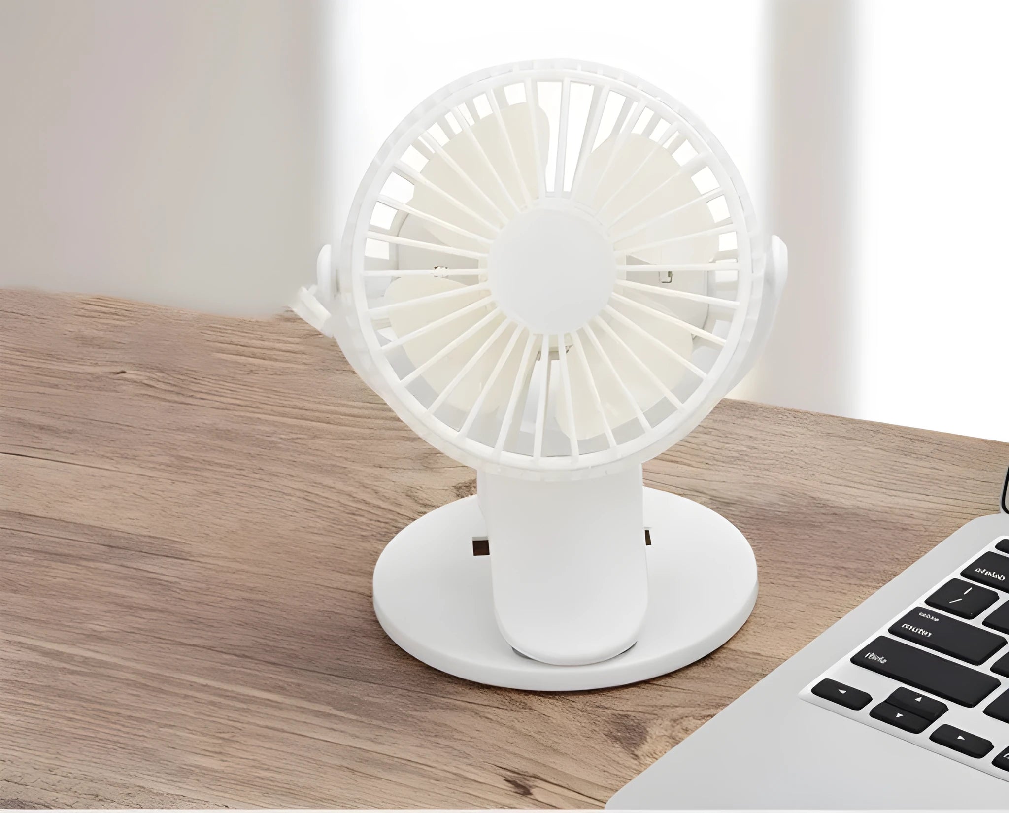 White USB rechargeable clip-on mini fan with plastic blades and a black clip, shown on a desk.