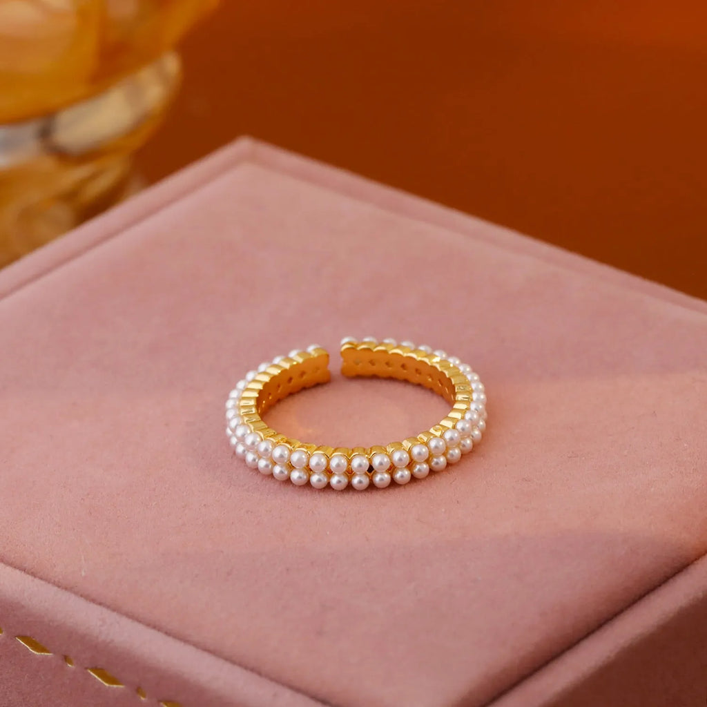 Gold geometric open ring for women with a pearl centre on a white background.