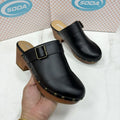Women's black chunky heel slippers with rivet details and closed toe on a rubber sole.