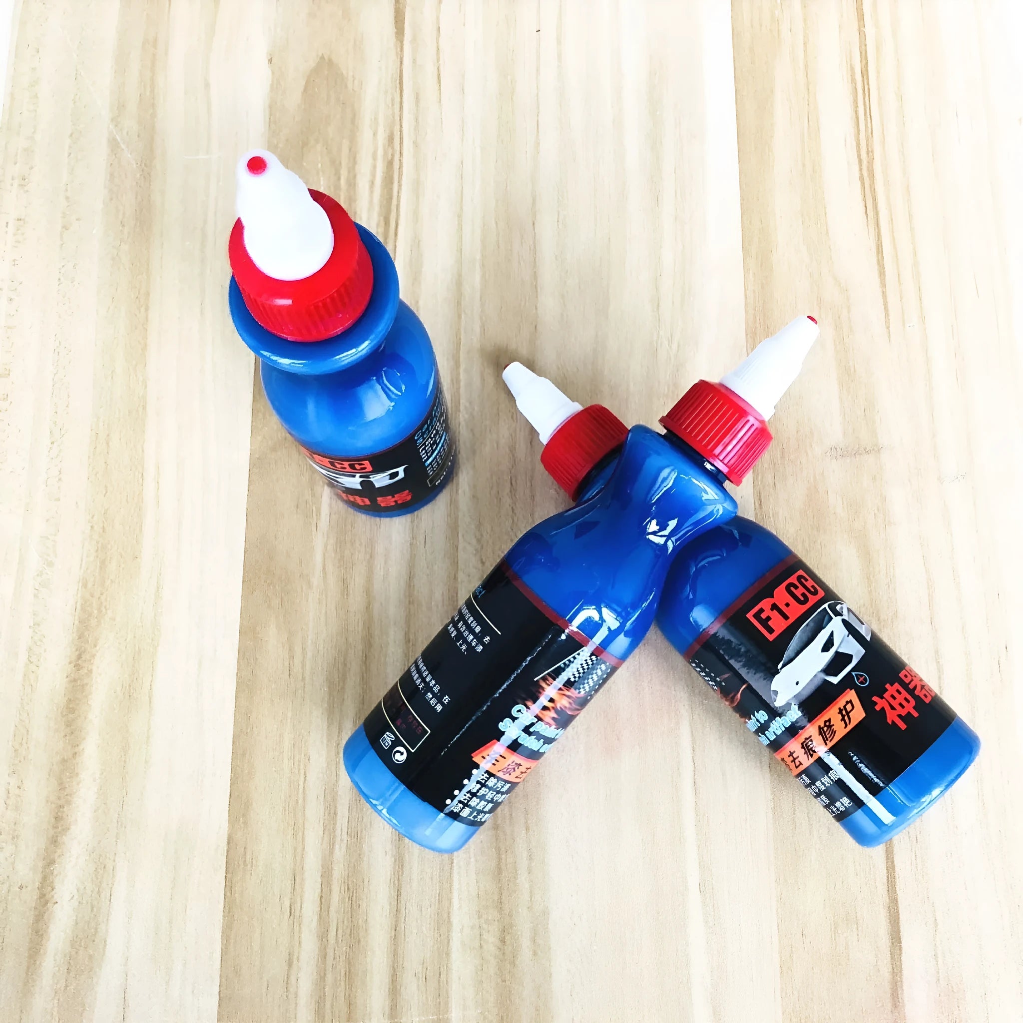 Small blue car wiping tool and bottle of scratch repair agent for DIY automotive scratch removal.