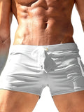 Men's solid colour polyester swimming trunks with lace-up waistband shown in black, dark blue, white, and red options