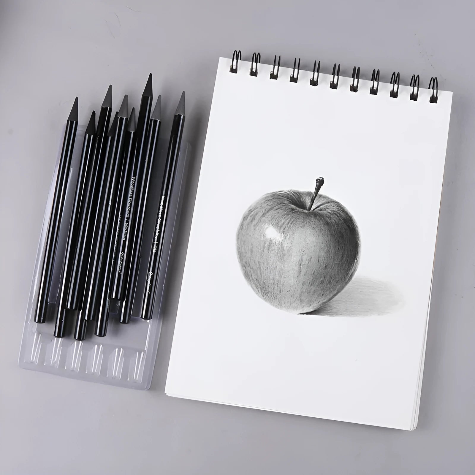 Set of nine art pencils on a card: six graphite pencils and three darker carbonized pencils in wooden casings.