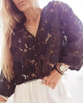 Black lace v-neck cardigan with three-dimensional white flower decorations on the sleeves.