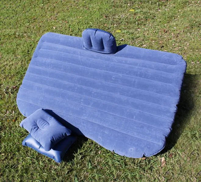 Black inflatable car bed with flocked texture and two pillows, shown inside a car boot.