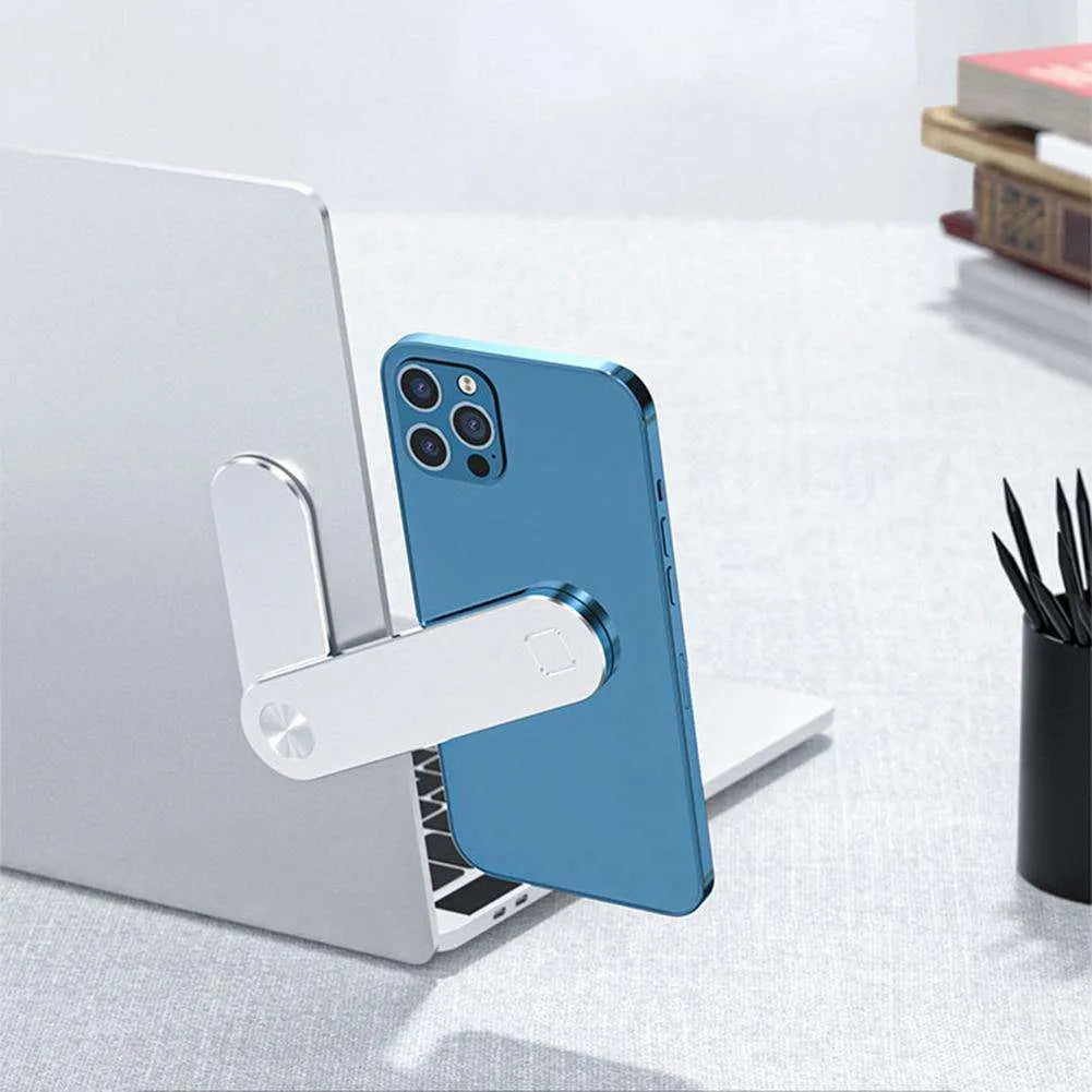 Black magnetic phone holder clipped to the side of a silver laptop, showing a smartphone attached.