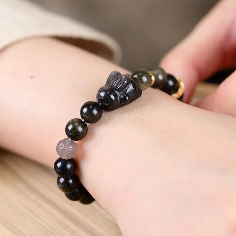 Handmade Chinese style bracelet with lying rabbit charm, grey agate bead, and brass on a black background.