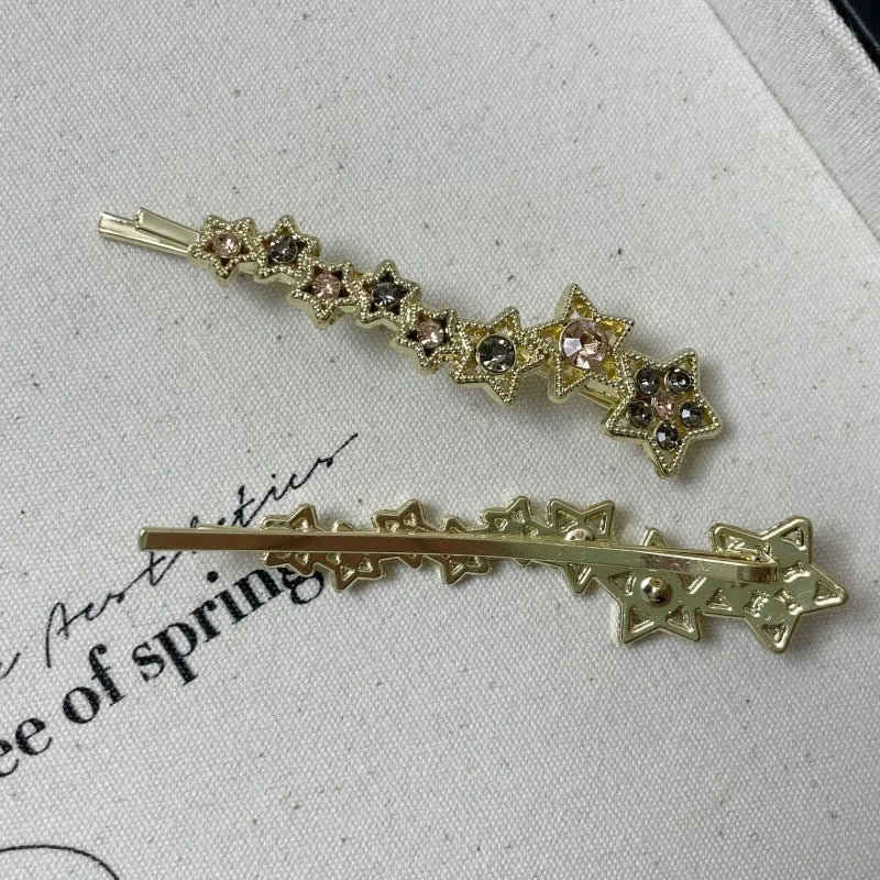Golden alloy barrette hair clip with rhinestone star decoration and single-word element.