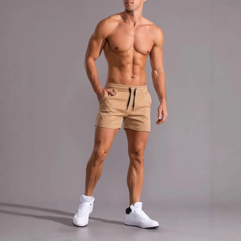 Three pairs of solid colour men's drawstring shorts in black, khaki, and light brown laid flat.