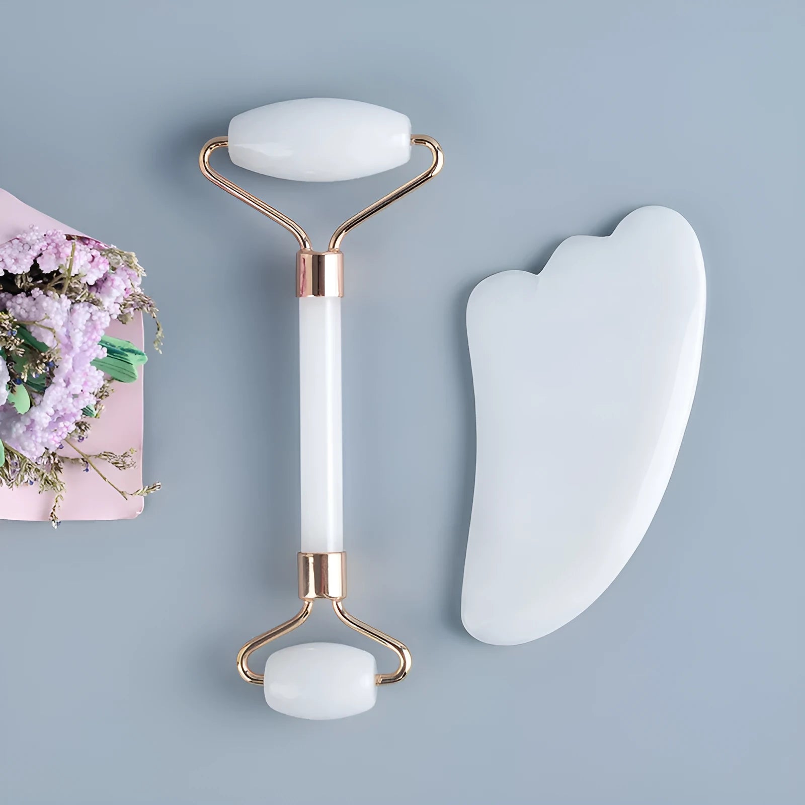 White jade facial roller and gua sha scraping tool set on a storage board.