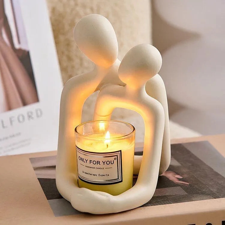 Modern minimalist loving couple resin statue in milky white or gold finish on a desk.