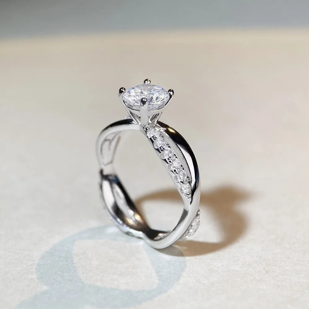 Geometric silver ring with twisted band and a 1 karat moissanite stone in a four-claw setting.