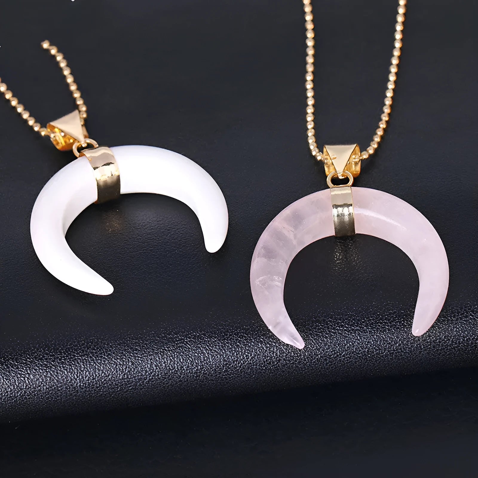 A moon-shaped pendant necklace with a pink natural stone on a copper-coloured chain against a white background.