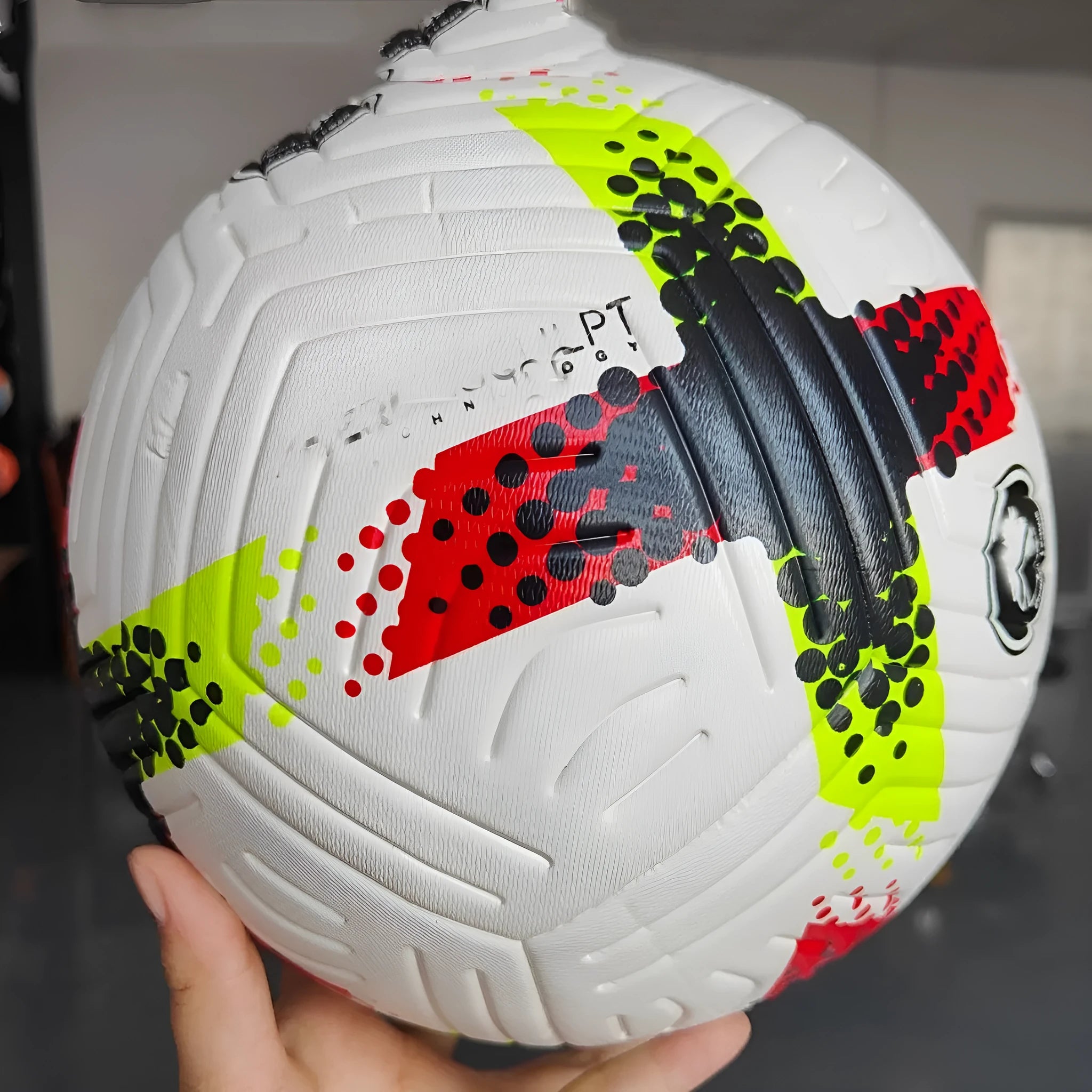 Fluorescent green Size 5 PU football with seamless thermal adhesive patch construction on grass.