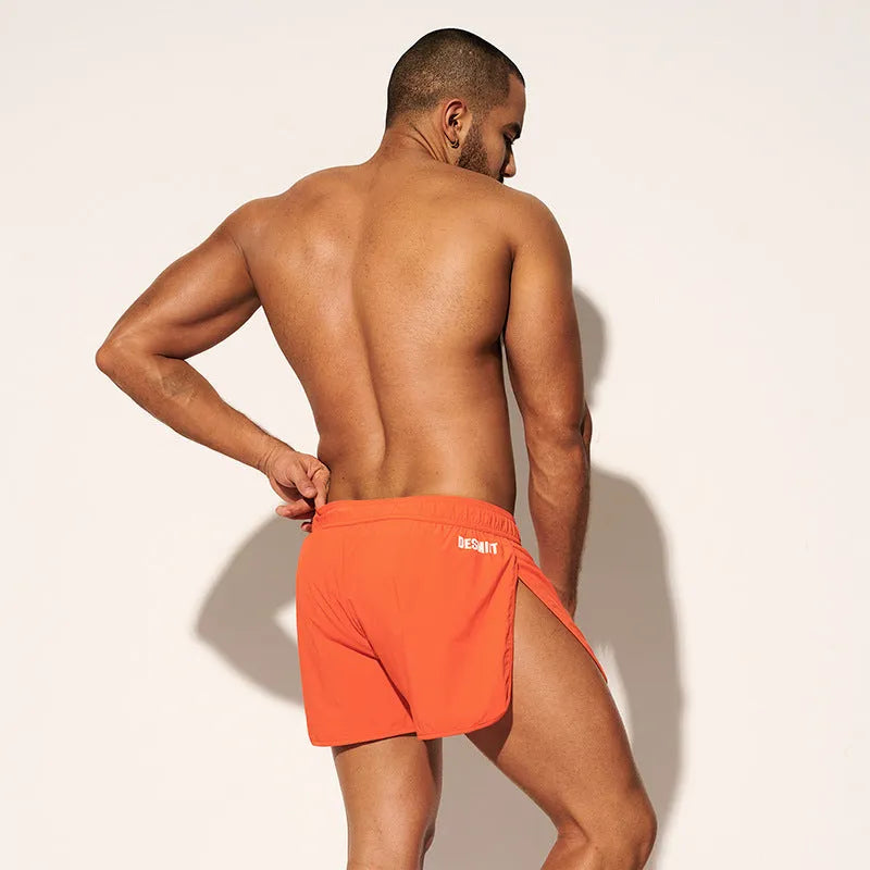 Men's loose orange polyester beach surfing trousers with elasticated fit on a size chart.