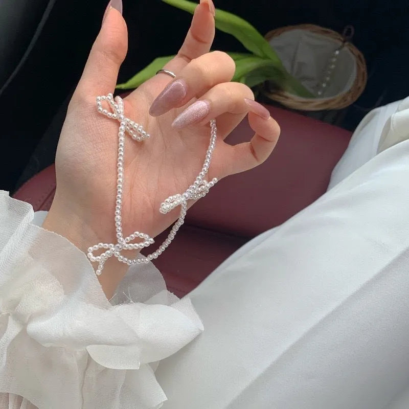 White imitation pearl necklace with a geometric bow charm on an adjustable chain.
