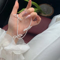 White imitation pearl necklace with a geometric bow charm on an adjustable chain.