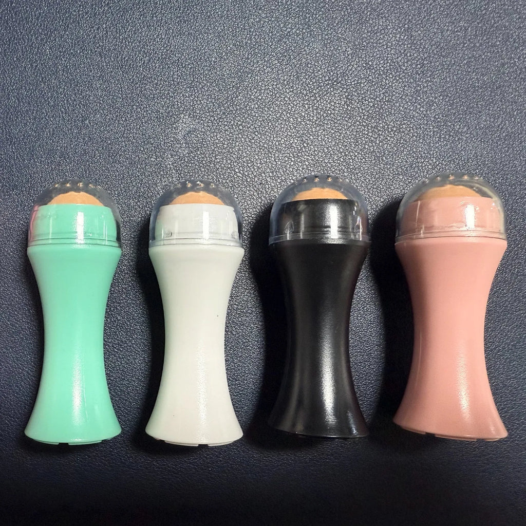 Volcanic stone portable roller for oily skin in black, green, pink or white on a grey background.