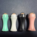 Volcanic stone portable roller for oily skin in black, green, pink or white on a grey background.