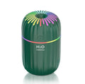 White USB mini humidifier with water tank on desk next to laptop