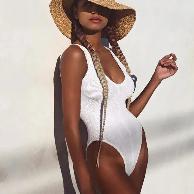 Solid colour women's one-piece swimsuit in wrinkled seersucker fabric, showing backless design.