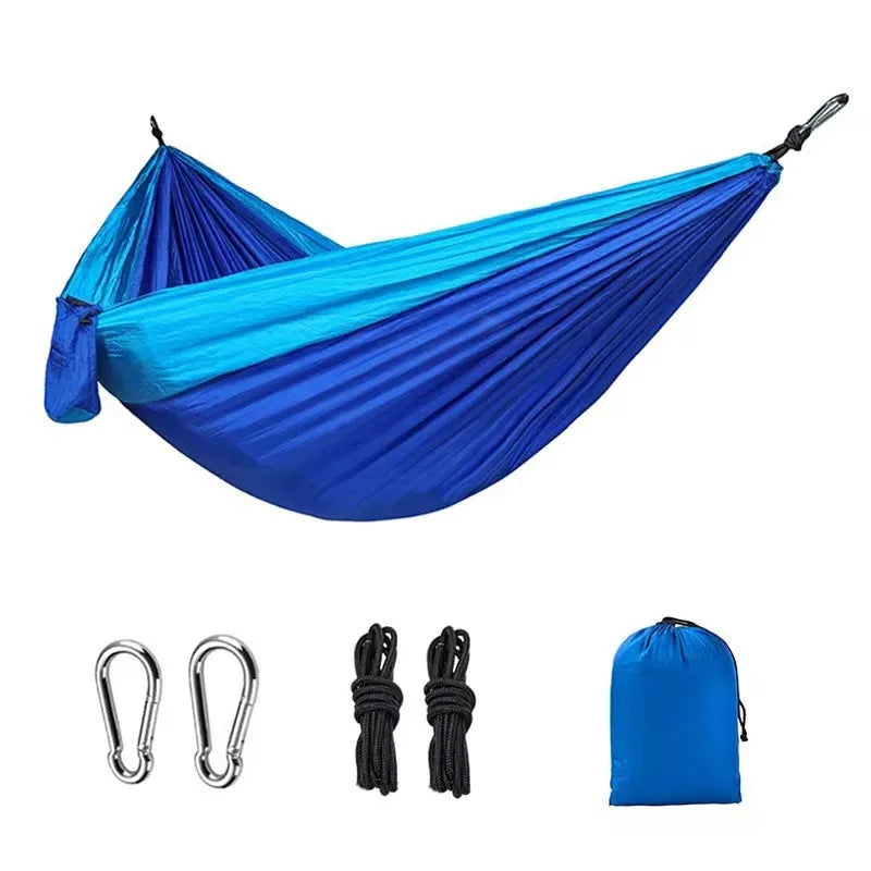 Blue parachute nylon camping hammock hung between two trees showing its full 270 cm length.