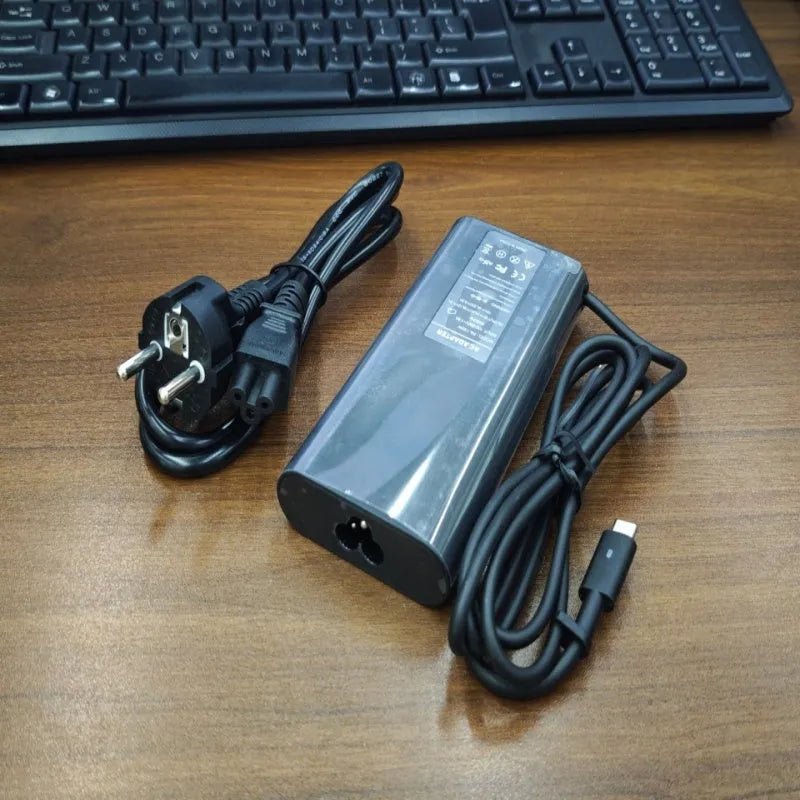 Black 65W Type-C laptop power adapter with multiple international plug heads on a white background.