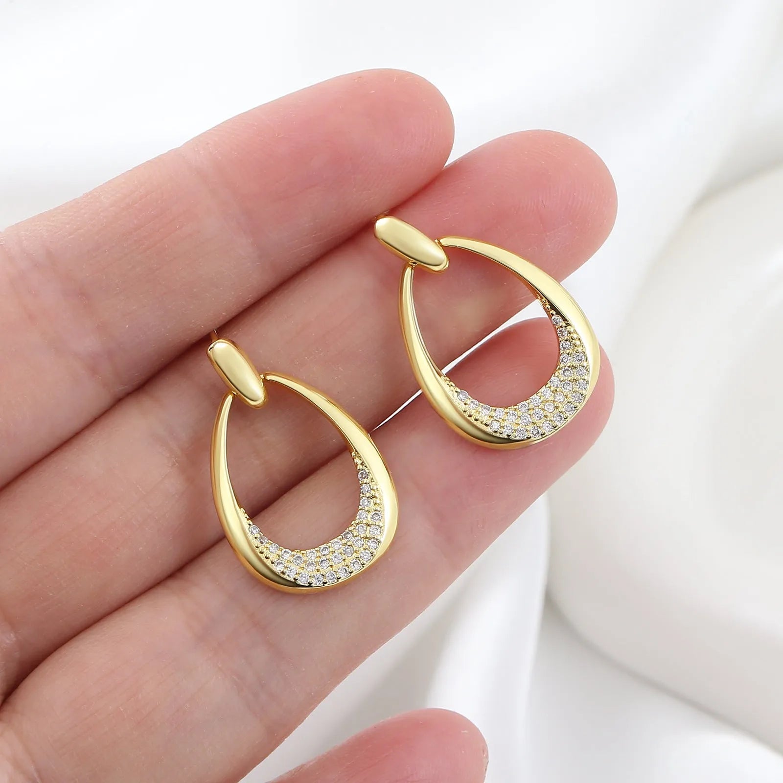 Women's yellow gold geometric drop-shaped earrings with ring design and zircon accents on a white background.