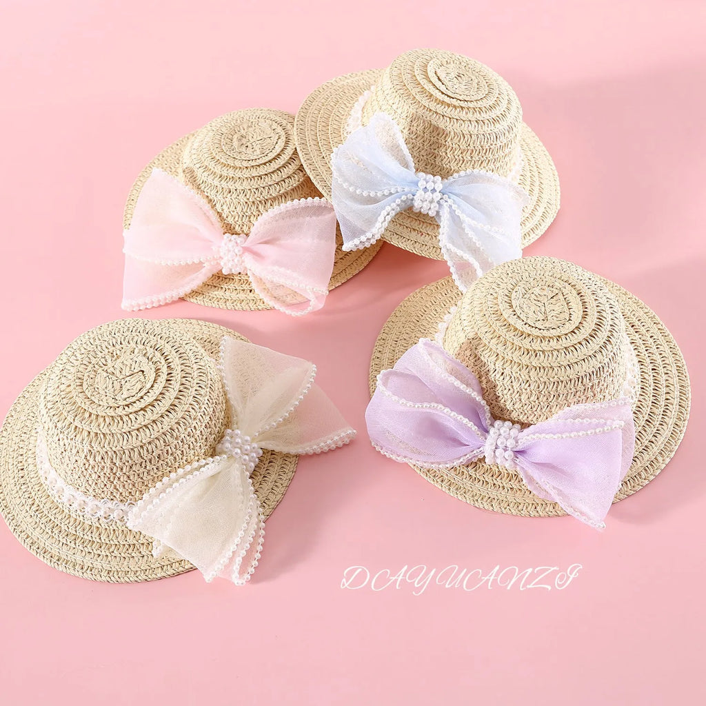 Cat wearing a woven straw hat with a pearl butterfly bow on its head.
