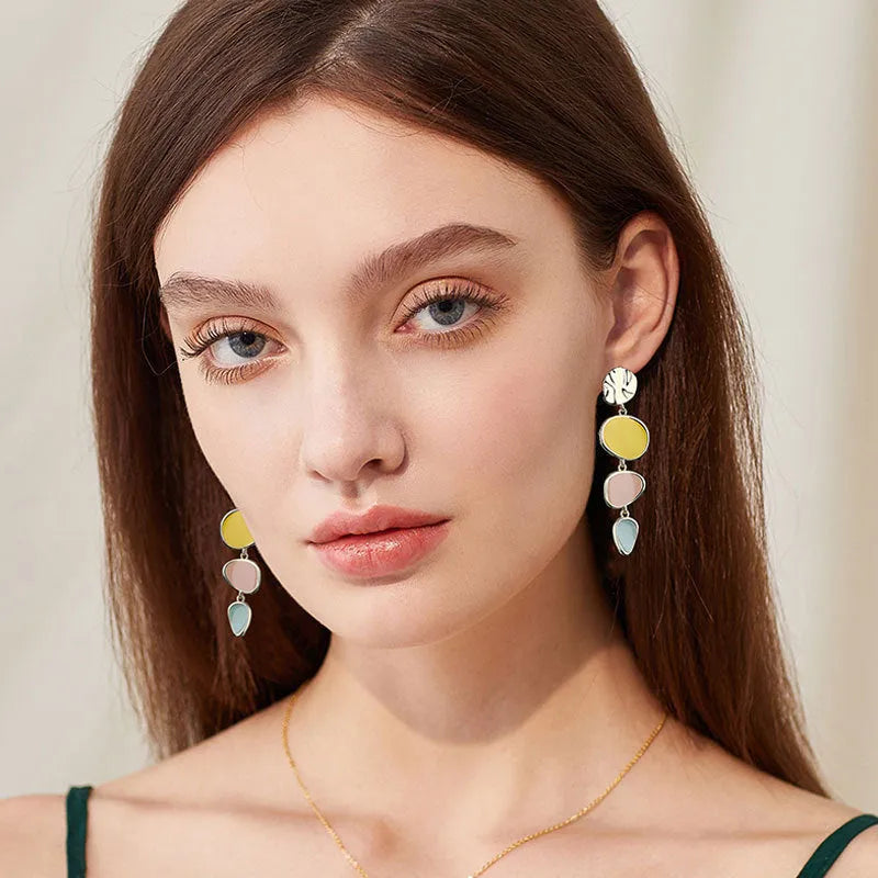 A pair of simple disc-shaped alloy earrings with a blended Morandi three-colour oil drip finish, showing a vintage wafer style.