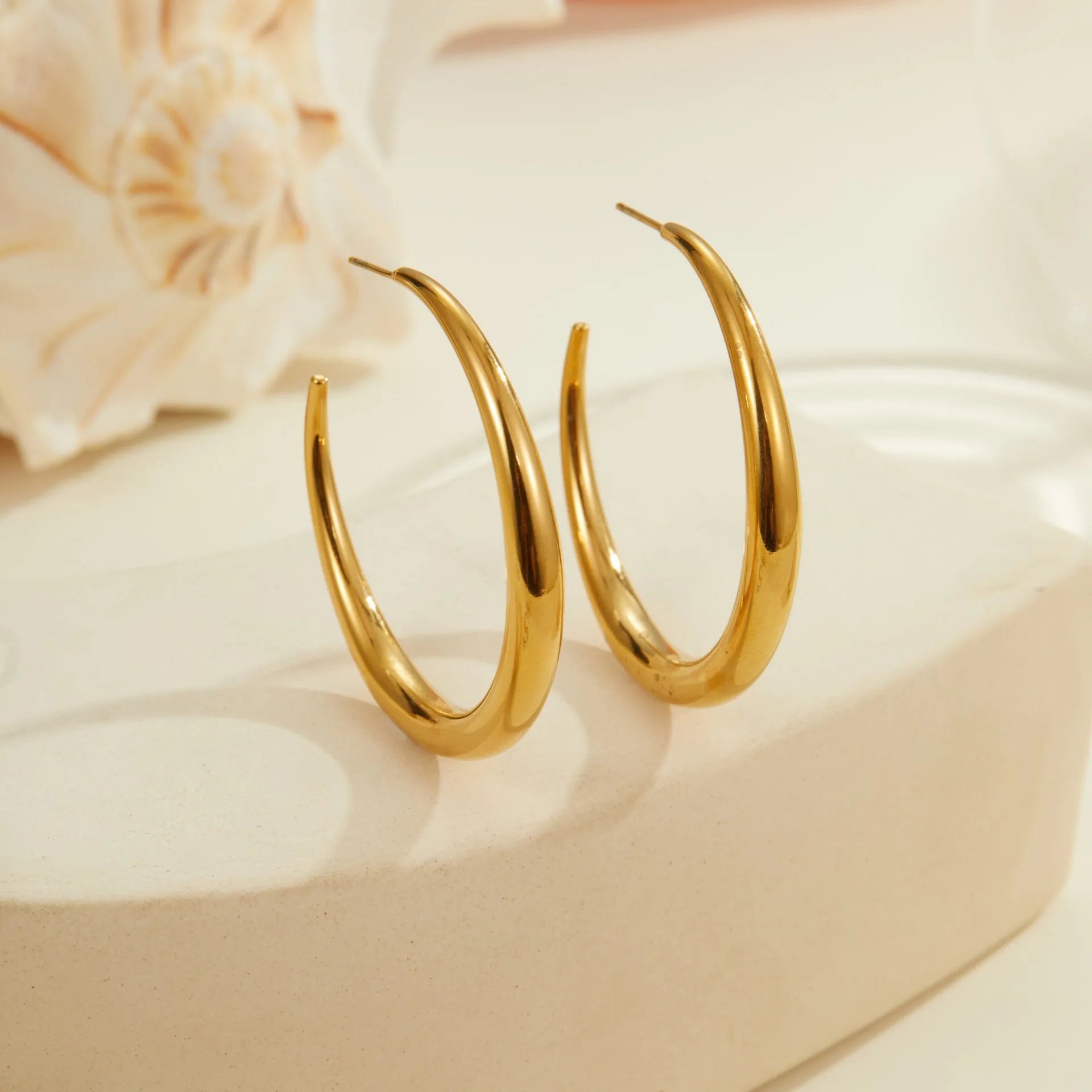 A pair of simple round titanium steel hoop earrings for women, shown in gold and steel finishes.