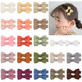 Assortment of pastel coloured baby hair clips and bows, including barrettes, laid out on a white background.
