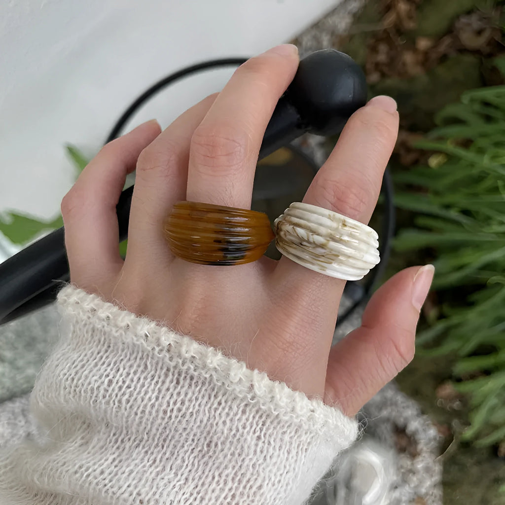 Chinese style irregular wide geometric resin ring in brown or white on display.
