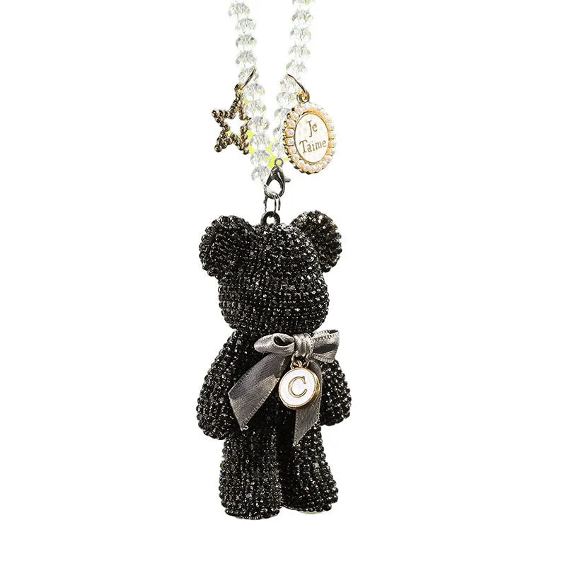 Close-up of a black Violent Bear-shaped car pendant with sparkling rhinestones, hanging from a rearview mirror.