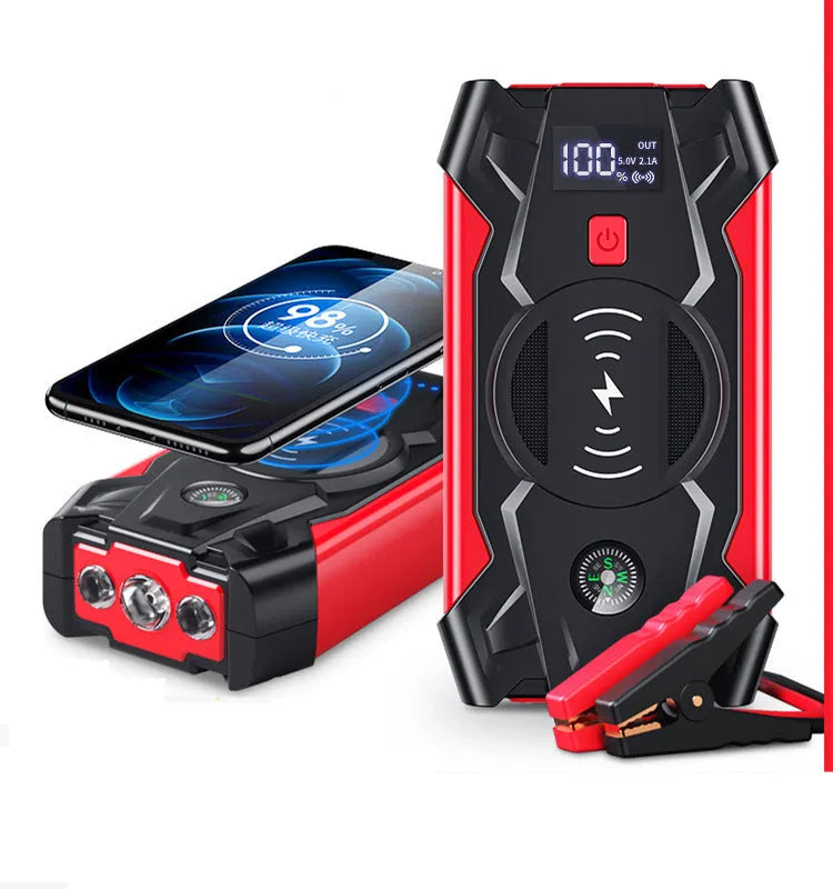 Red portable car jump starter and power bank unit with jumper cables on a table