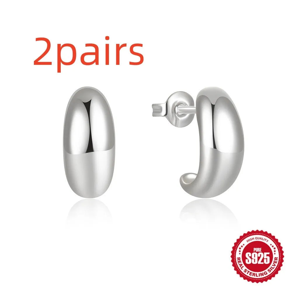 A single glossy C-shaped sterling silver stud earring on a plain background, showing gold and silver finish options.