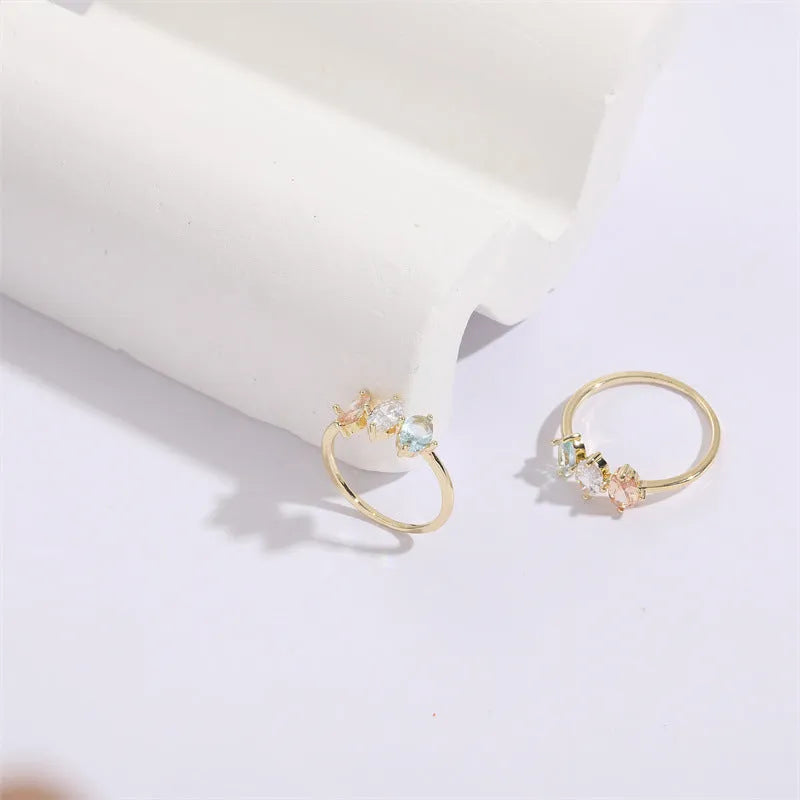 Geometric triangle birthstone ring with tricolour zircon and horse eye motif in gold plating.