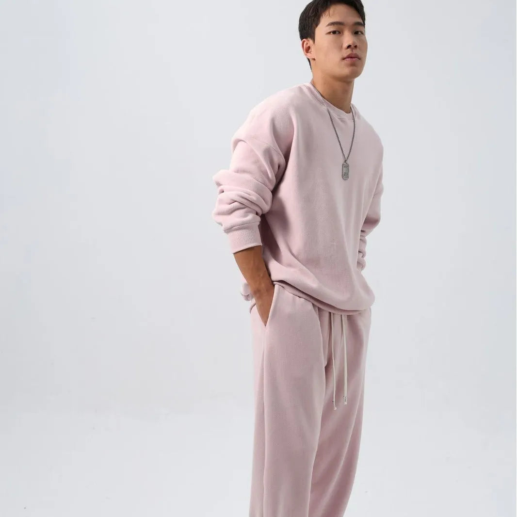 Man wearing a grey polar fleece crew neck coat and matching padded trousers from a casual winter sport suit set.