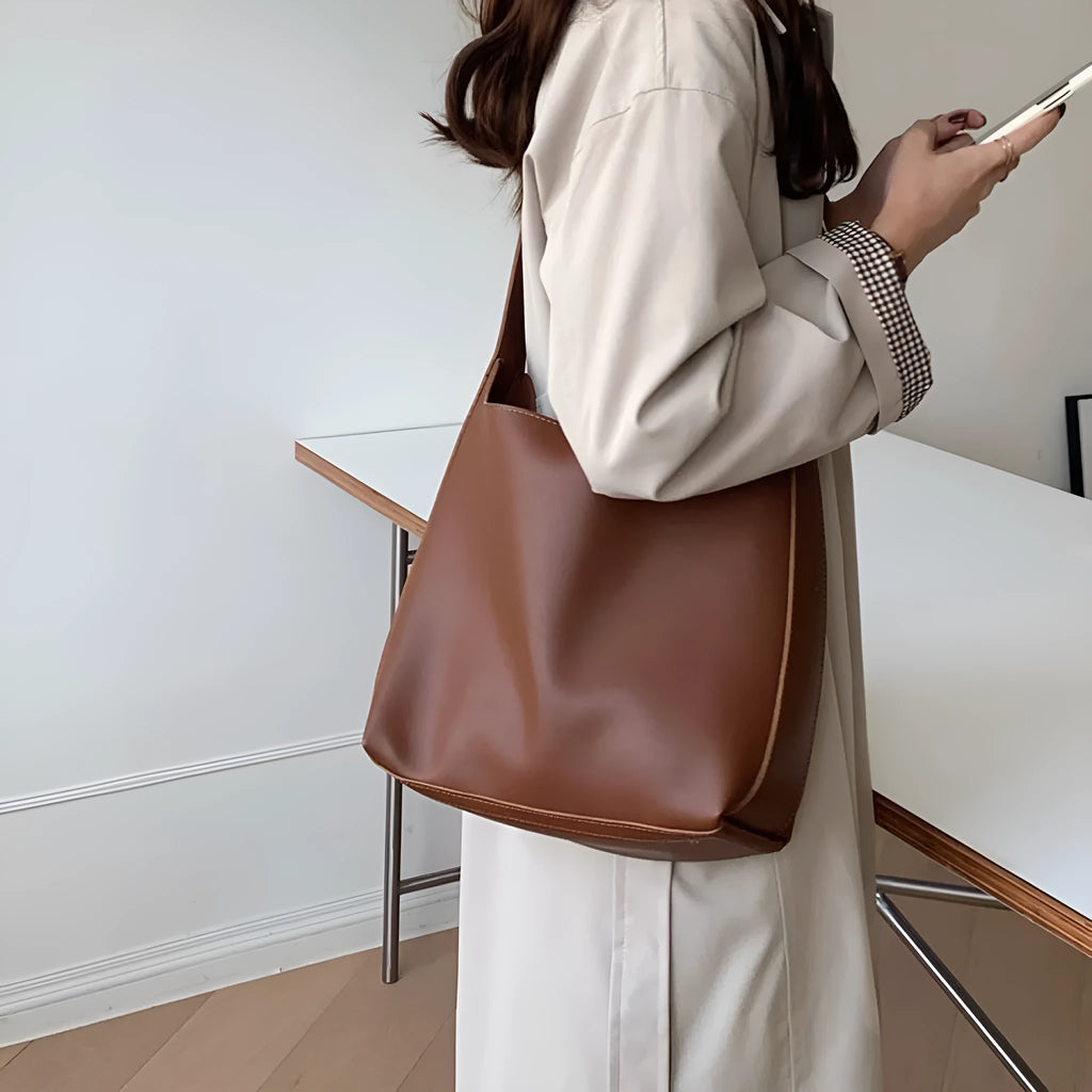 Two women's fashion shoulder bags in black and brown PU leather with swing thread details