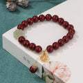 Women's handmade cinnabar bracelet with fu character charm and tassel detail in purple gold sand finish