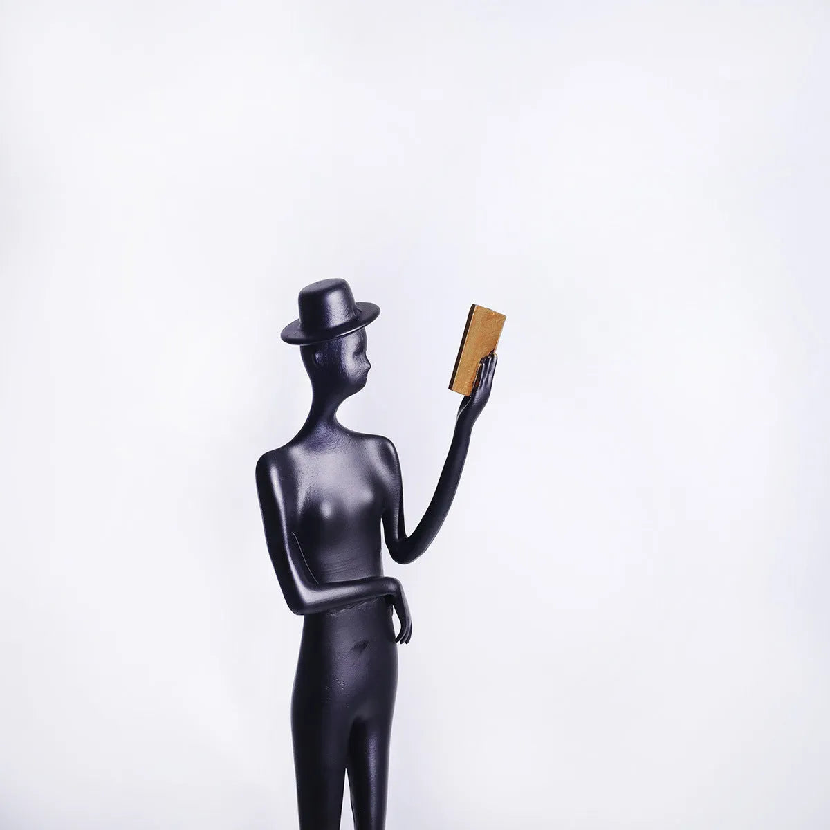Black aluminium desktop sculpture of a woman reading, modern style.