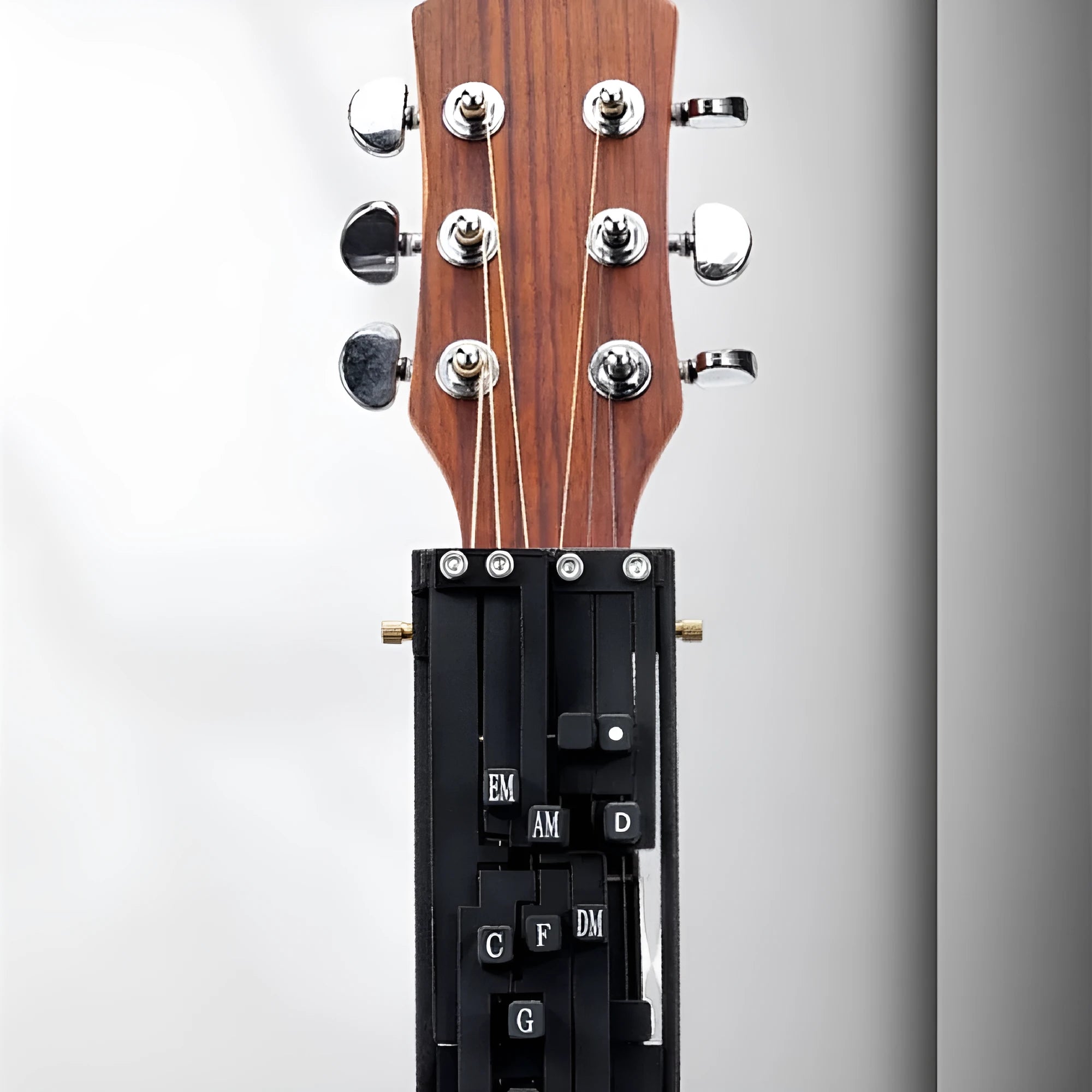 Black automatic guitar chord practice device for novice players on a folk guitar.